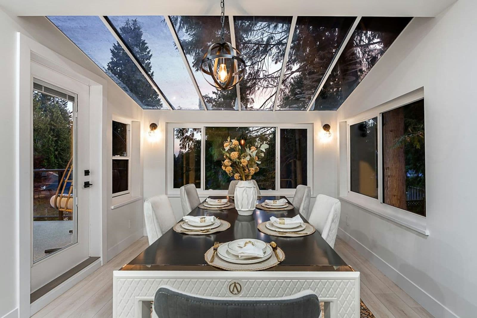 Elegant staged dining room set beneath a glass sunroom ceiling