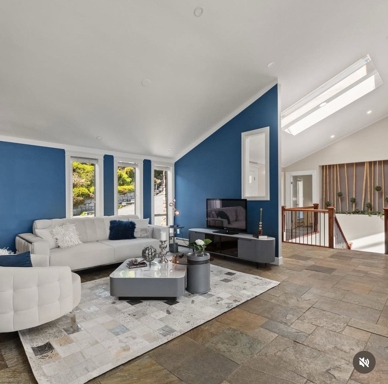 Staged living room with a blue feature wall, slate floor and a bright skylight