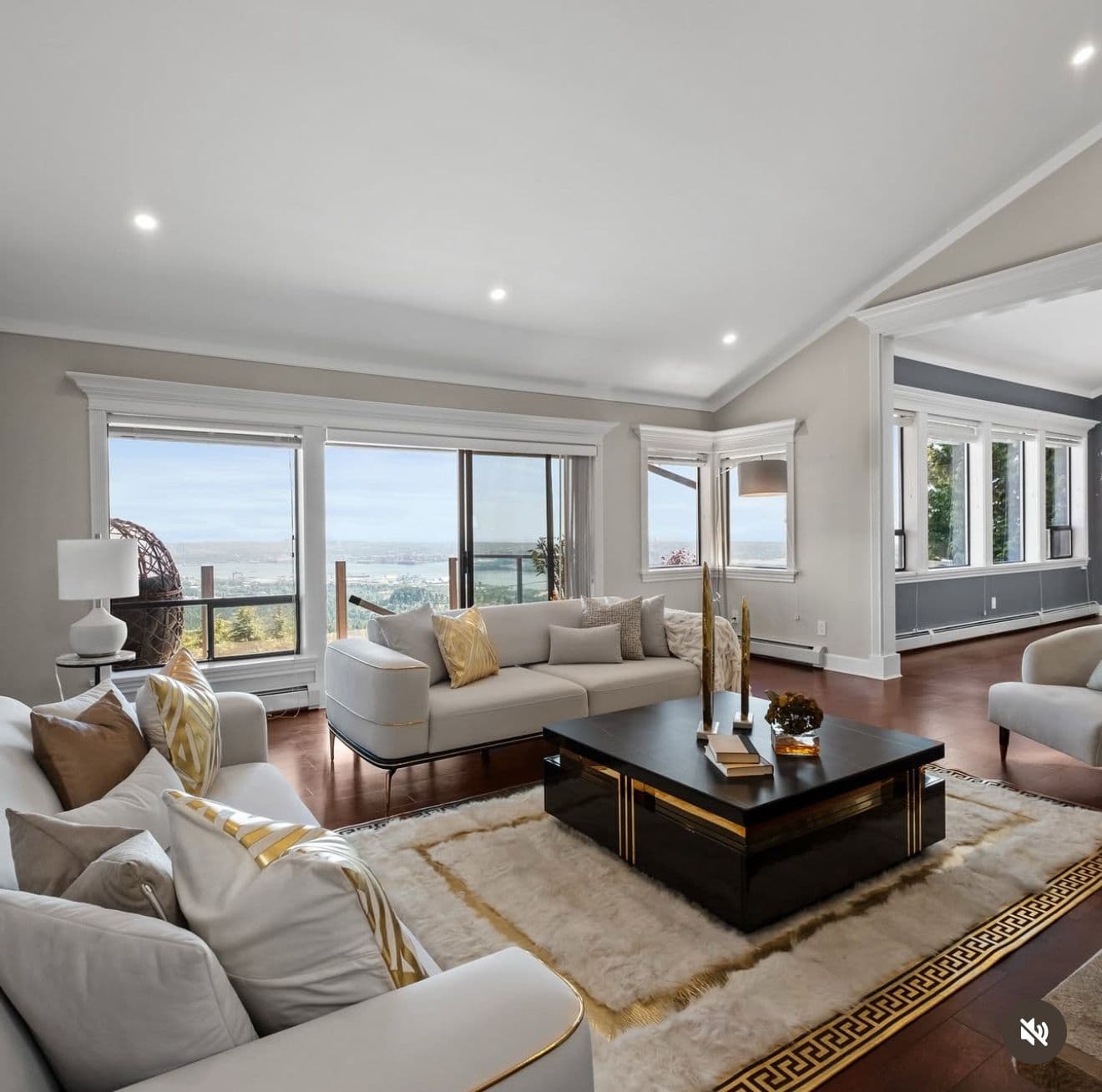 Staged living room with gold accents, a Greek-key rug and panoramic city and water views