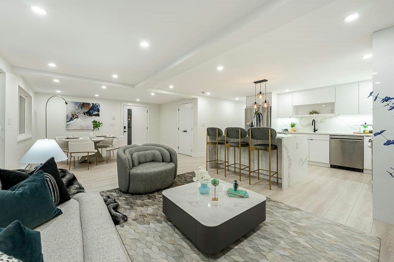 Open-plan staged living and marble kitchen with a grey bouclé swivel chair