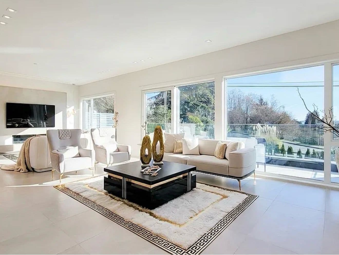 Staged living room with a Greek-key rug, wingback chairs and a bright outlook